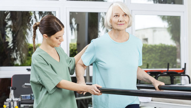 therapist helping senior exercise