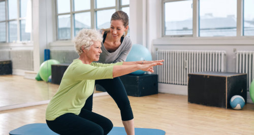 old woman assisted by her coach workout